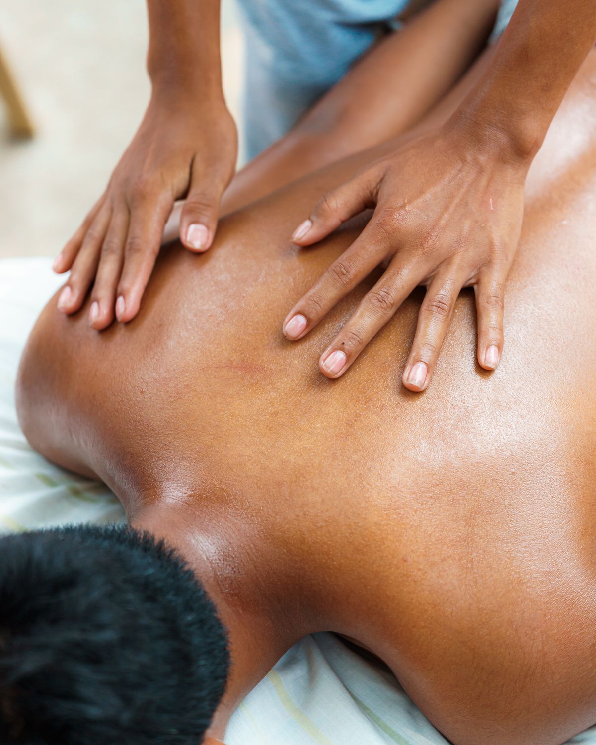 Therapist performing a back massage in a calm, softly lit studio